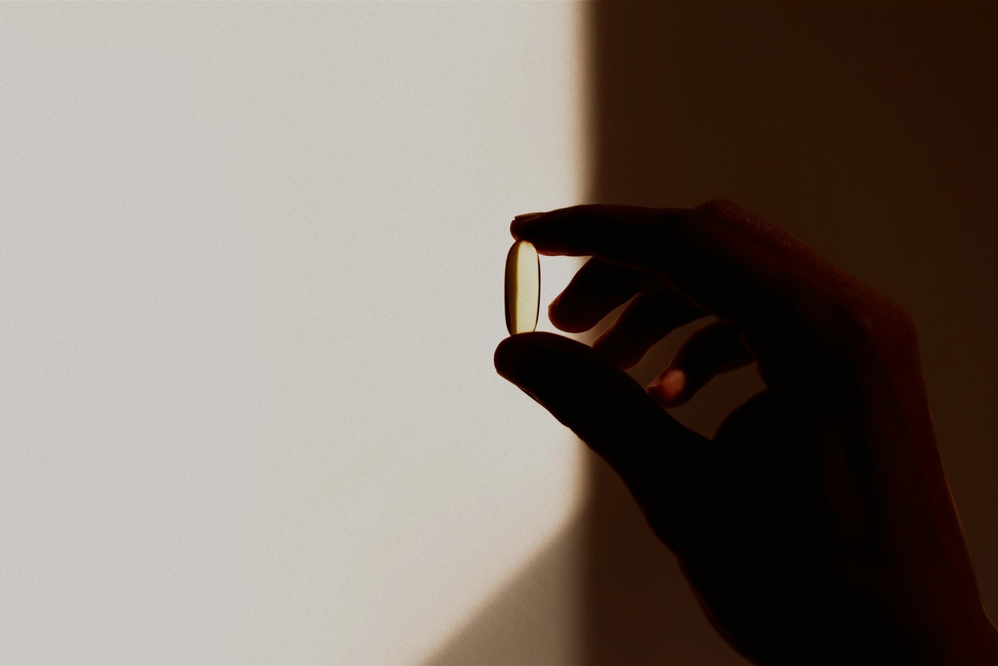 A hand holding supplement capsules.